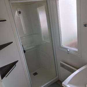 La salle de bains est pourvue d'une porte de douche en verre à côté d'un lavabo. dans l'établissement Mobil-Home Clos 14 à VIAS, à Vias
