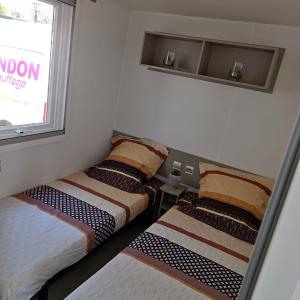 - 2 lits installés à côté d'une fenêtre dans une pièce dans l'établissement Mobil-Home Clos 14 à VIAS, à Vias