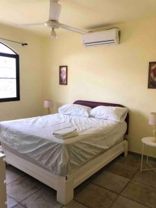 Schlafzimmer mit einem Bett mit weißer Bettwäsche und einem Ventilator in der Unterkunft Lovely 2B/1B condo only 5 min walk to the beach. in Bayahibe