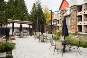 a patio with tables and chairs and umbrellas at Lake Placid Lodge by Outpost Whistler in Whistler
