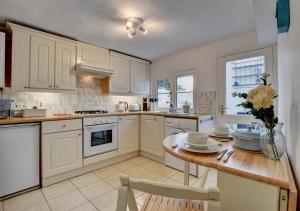 a kitchen with white cabinets and a wooden table at Whimbrel Cottage in Appledore