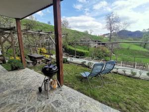 eine Terrasse mit zwei Stühlen und einem Grill auf dem Rasen in der Unterkunft Apartment Rakušček in Kobarid