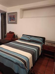 a bedroom with a bed with a striped blanket on it at Departamento allende antiguo in Oaxaca City