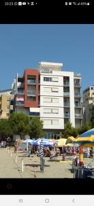 een strand met parasols en een groot gebouw bij Mani Apartment in Durrës
