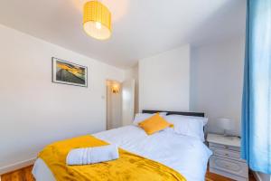 1 dormitorio con cama blanca y manta amarilla en Stylish 3-bed Apartment with Free Parking and Wi-Fi en Chatham