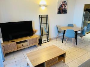 a living room with a flat screen tv and a table at Appartement VAIANA avec piscine en bord de mer in Ajaccio