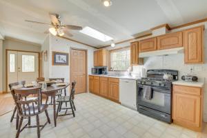 a kitchen with wooden cabinets and a table and a dining room at Cozy Midcoast Vacation Rental Near Waterville! 