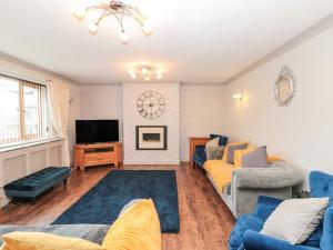 uma sala de estar com sofás azuis e uma televisão em 5 Westwood Road em Scarborough