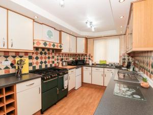 uma grande cozinha com armários brancos e electrodomésticos pretos em 5 Westwood Road em Scarborough