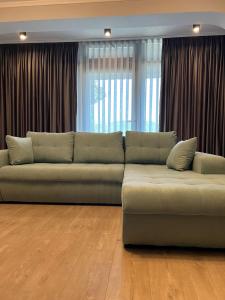 um sofá sentado numa sala de estar com cortinas em Apart Central em Orşova