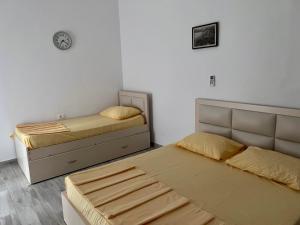 a room with two beds and a clock on the wall at Perdja Apartment I in Velipojë
