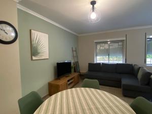 a living room with a couch and a table and a clock at Apartamento flor de amendoeira in Albufeira +9 photos