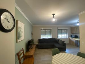 - un salon avec un canapé et un réveil sur le mur dans l'établissement Apartamento flor de amendoeira, à Albufeira