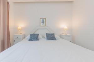 - un lit blanc avec 2 oreillers bleus dans l'établissement Luxury Apartment Slavica by the sea,with garden, à Sukošan