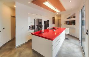 une cuisine avec un comptoir rouge et des armoires blanches dans l'établissement Beautiful Home In Portiragnes With Kitchen, à Portiragnes