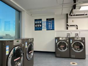 a laundry room with three washing machines and a window at Beachfront Double Queen - CozySuites in Atlantic City
