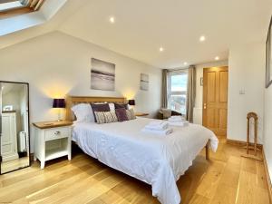 a bedroom with a large white bed and a window at Wickland Cottage in Chichester