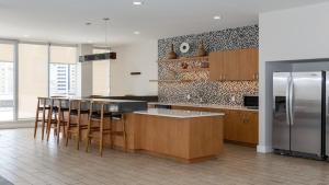 uma cozinha com armários de madeira e um frigorífico de aço inoxidável em Bold CozySuites with pool, gym, roof #8 em Dallas