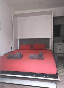 Una gran cama roja con dos toallas. en chambre 2 pas du centre-ville, en Gisors
