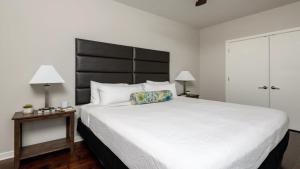 a bedroom with a large white bed with a black headboard at Bold CozySuites with gym, roof #3 in Dallas