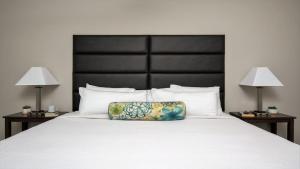 a large bed with a pillow on it with two lamps at Bold CozySuites with gym, roof #7 in Dallas +17 photos