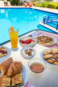una mesa con platos de comida y bebida junto a una piscina en Studios Suzanna, en Potos