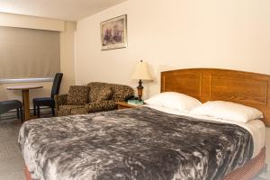 um quarto de hotel com uma cama grande e uma cadeira em Grandview Motel em Kamloops