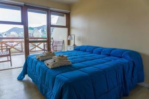 uma cama azul num quarto com uma janela grande em Gente del Sur - Odino em Ushuaia