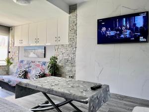 a living room with a table and a tv on a wall at La Pineda playa in La Pineda
