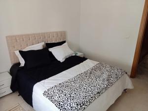 a bedroom with a bed with a black and white blanket at La perle bleue de Sarah in Kheredine