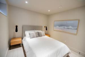 ein Schlafzimmer mit einem weißen Bett und einem Gemälde an der Wand in der Unterkunft 4 Bedroom Lakefront House by Leavetown Vacations in Lakefield