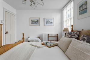 a white bedroom with a bed and a window at The Admiralty Wash House in Dartmouth