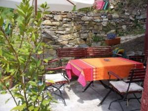 een patio met een tafel en stoelen en een stenen muur bij Casa Rosalie in Borgomaro