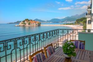 a balcony with a table and chairs and a beach at Montesan Luxury Apartment in Sveti Stefan