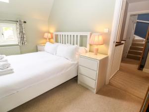 a bedroom with a bed and a night stand with two lamps at 3 Painters Field in Cirencester