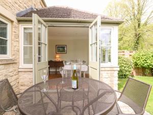 a glass table with two wine glasses on a patio at 3 Painters Field in Cirencester