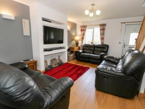 a living room with leather furniture and a flat screen tv at 6 Stad Yr Ysgol in Blaenau-Ffestiniog