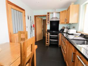 uma cozinha com armários de madeira e um forno de fogão preto em 6 Stad Yr Ysgol em Blaenau-Ffestiniog