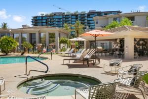 a pool with chairs and tables and a building at Golf Lover's CozySuites Kierland Commons in Scottsdale