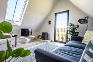 uma sala de estar com um sofá azul e uma televisão em Yoxford Farm Hayloft em Saxmundham