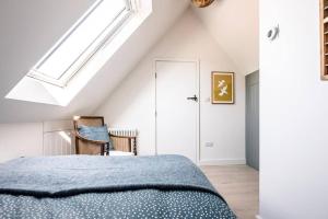 a bedroom with a blue bed and a skylight at Yoxford Farm Hayloft in Saxmundham