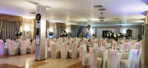 a room full of tables and chairs with white chairs at Hotel Suprem in Băile Olăneşti