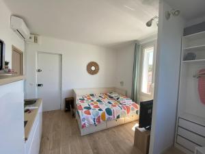 a small bedroom with a bed and a kitchen at Studio le Monroe les pieds dans l'eau 10 m de la mer in La Seyne-sur-Mer