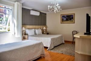 um quarto de hotel com duas camas e uma televisão em Chateau do Luar Prime em Campos do Jordao em Campos do Jordão