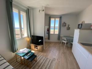 a living room with a television and a table at Studio le Monroe les pieds dans l'eau 10 m de la mer in La Seyne-sur-Mer