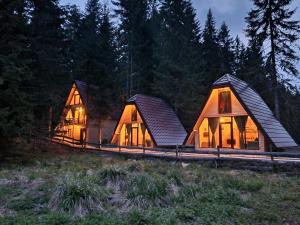 three wooden houses in a forest at night at Oaza Jela in Mitrovac