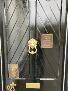 Eine schwarze Tür mit goldenem Griff und einem Schild darauf. in der Unterkunft Glenorchy Lodge-Rooms Only in Dalmally
