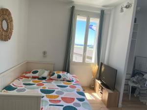 a bedroom with a bed with a colorful comforter and a television at Studio le Monroe les pieds dans l'eau 10 m de la mer in La Seyne-sur-Mer
