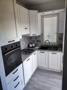 a kitchen with white cabinets and a black stove top oven at Apartman Valor in Rovinj +4 photos