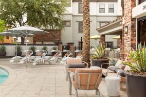 a patio with tables and chairs and a pool at CozySuites Glendale by the stadium with pool 10 in Glendale